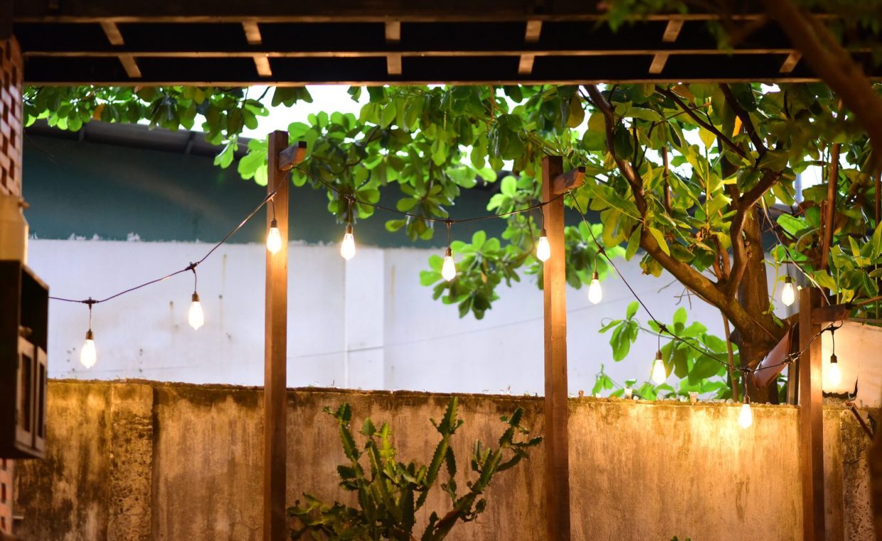 Warm string lights illuminate a backyard with lush foliage, creating a cozy outdoor ambiance.