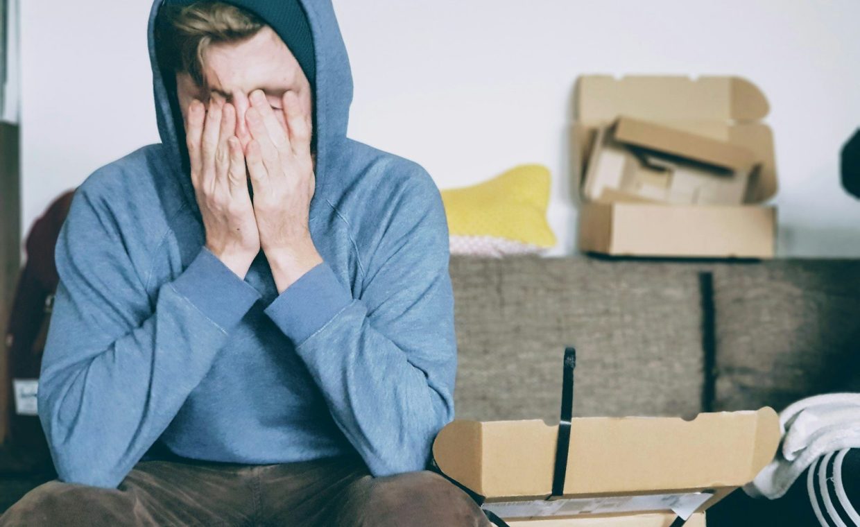 man covering face with both hands while sitting on bench