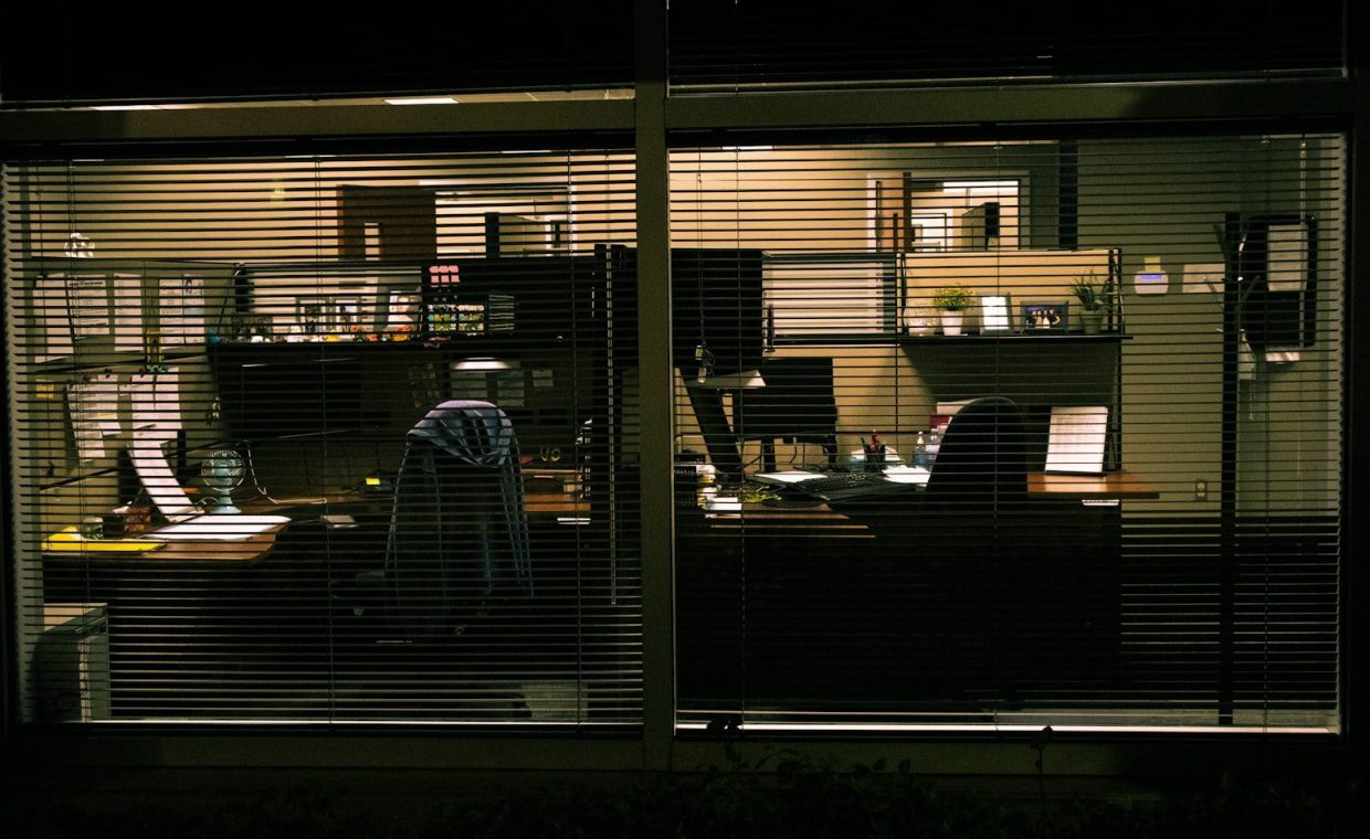 a view of a living room through blinds at night