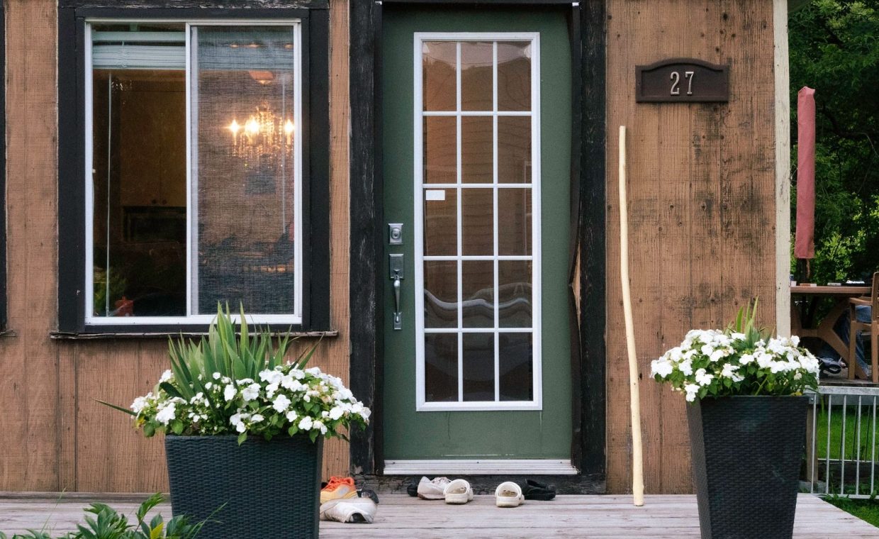 A charming rustic wooden house entrance with large potted flowers and inviting decor.