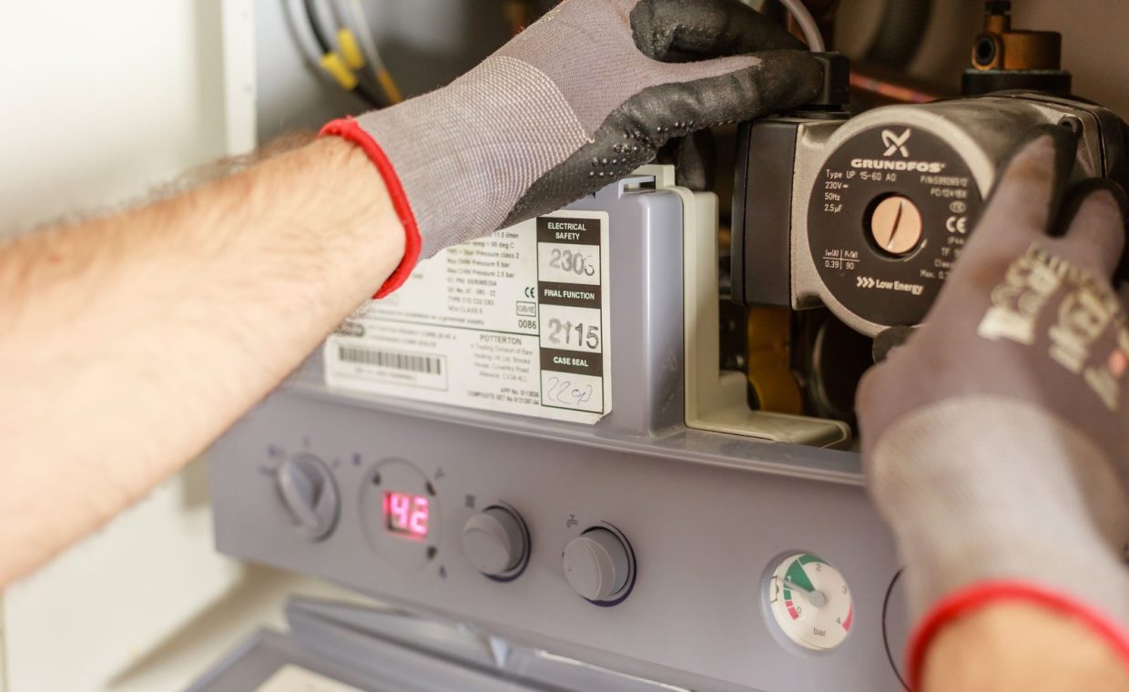 Close-up of hands adjusting a boiler system with precise instrumentation, showing maintenance work.