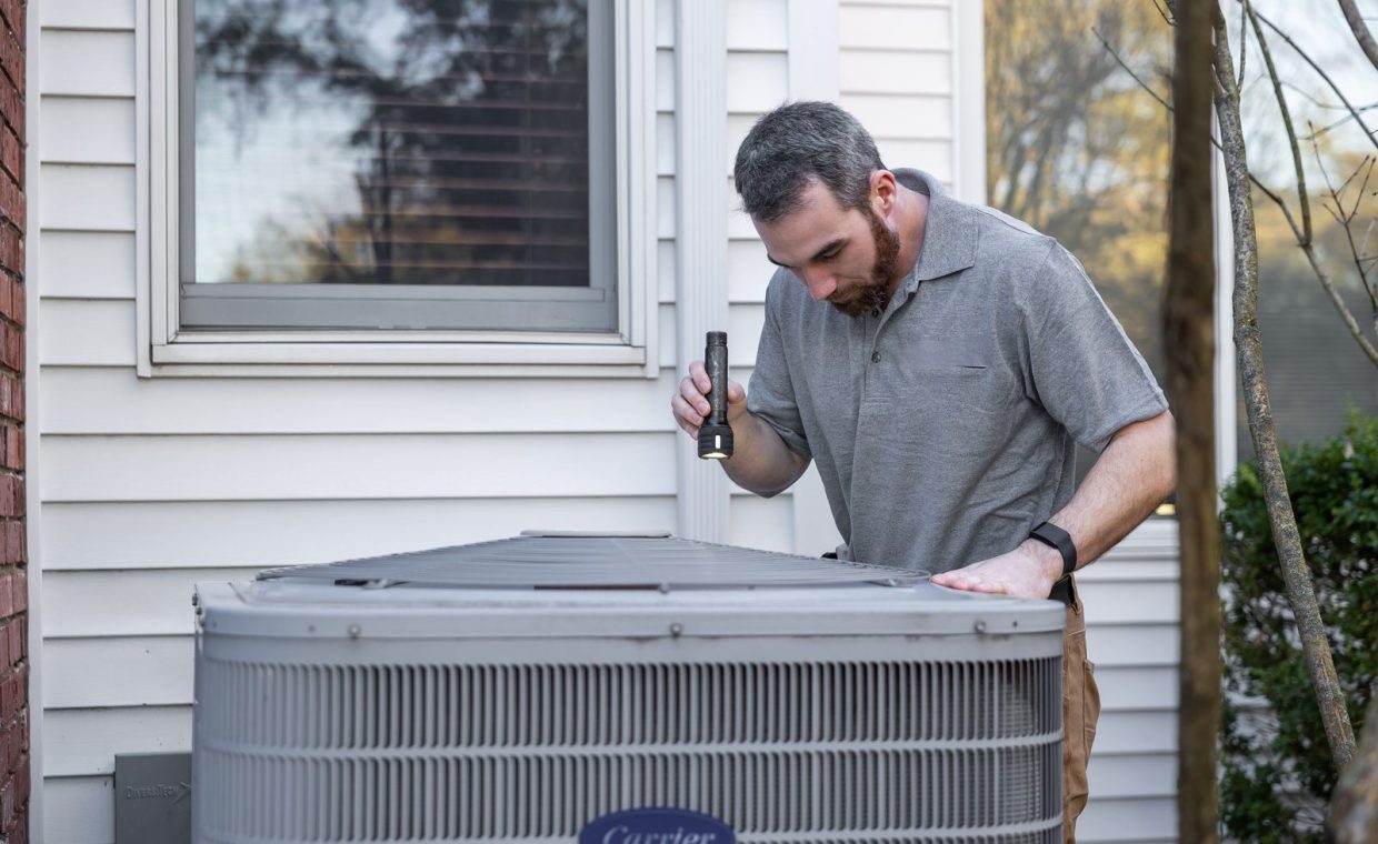 A technician inspects an outdoor HVAC unit for maintenance.