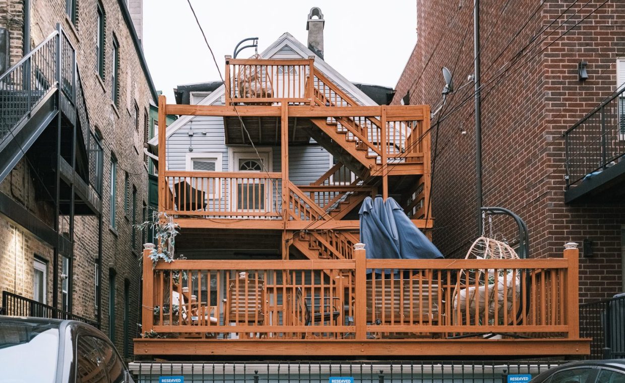 Multi-level wooden deck between urban buildings, showcasing unique architectural design.