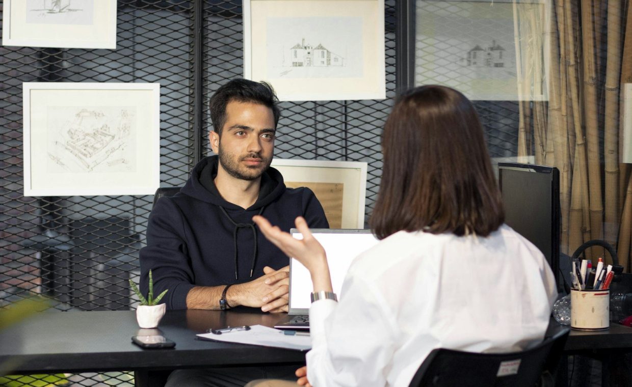 a man sitting at a desk talking to a woman
