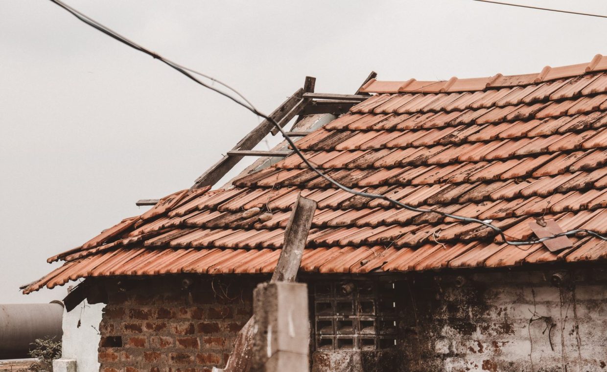 An old rural house with a damaged clay tile roof in Chennai, India, showing signs of decay.