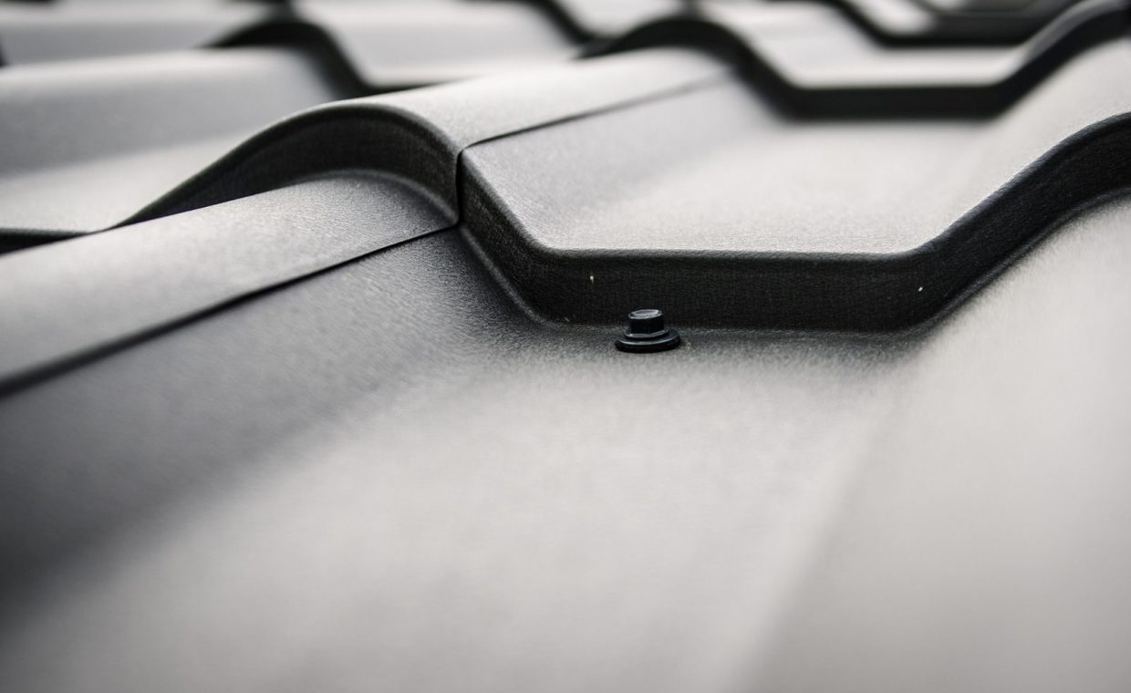 Detailed close-up of a black steel roof with prominent rivets and tiles.