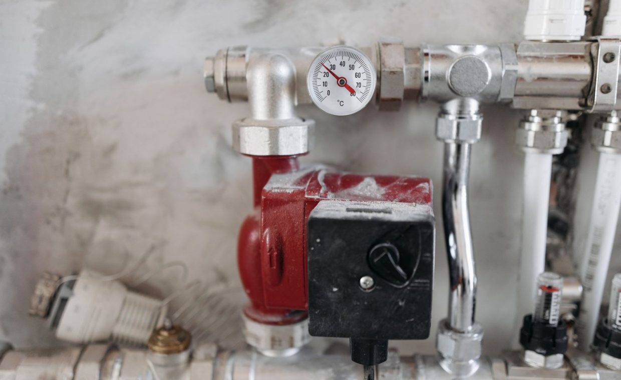 Close-up view of an industrial plumbing system featuring a pressure gauge and steel pipes.
